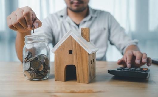 man puts money in a jar for house savings