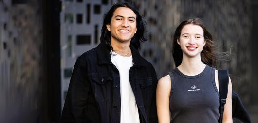 Two smiling students standing outside UTS building 11