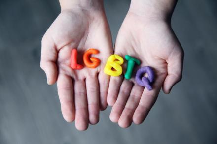Hands holding colorful Plasticine letters spelling LGBTQ