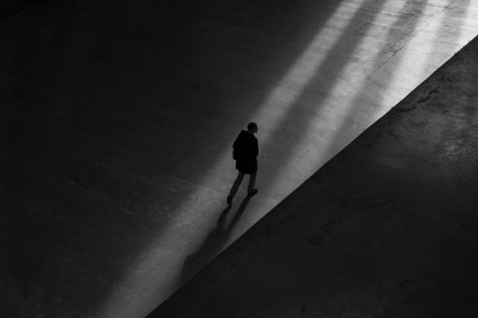 Man walking alone along a dark street with long shadows
