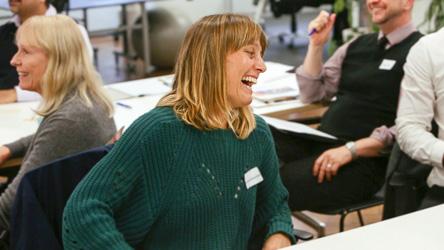 Photo of a woman laughing in a classroom setting