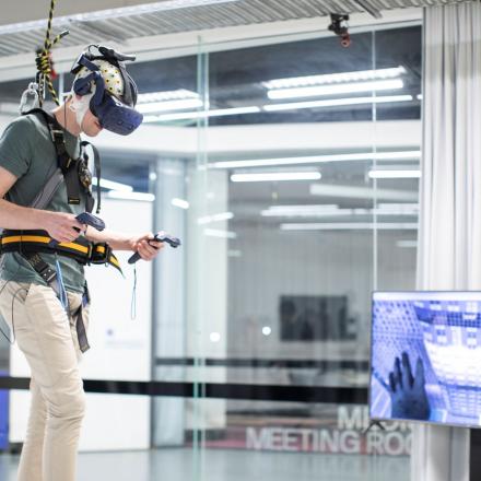 Student wearing an EEG headset with VR headset showing the virtual reality environment on top of a high rise building
