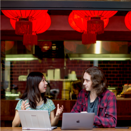 Two students sitting in an asian eatery with their laptops