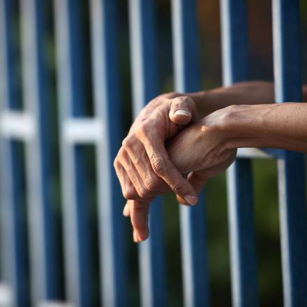 Hands rest on prison bars