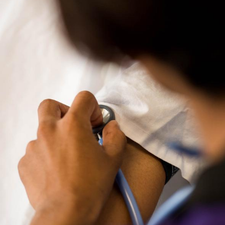 Health Professional checks patient's vital signs with stethoscope on arm