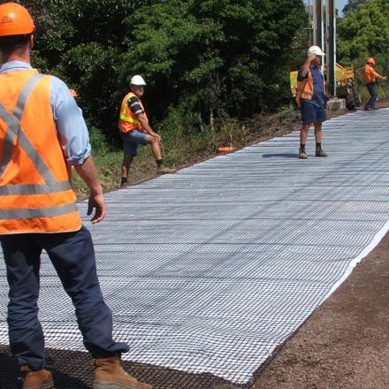 Workers in hi vis gear using geo-composite to stabilise rail track