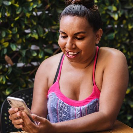 Aboriginal woman smiling looking at her mobile phone