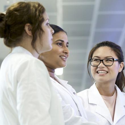 Three young female scientists in lab coats