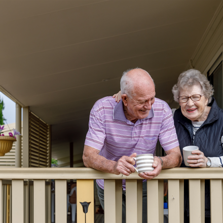 Two elderly people enjoying a cup of tea on their porch