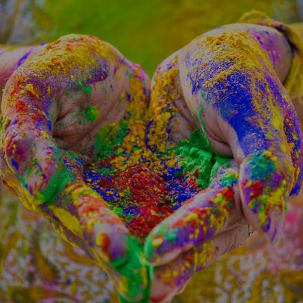 Hands in a heart shape covered in coloured powder for Holi celebrations