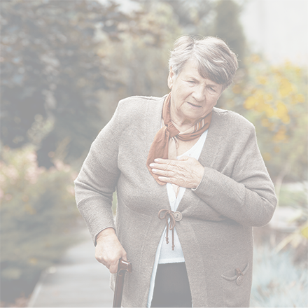 Weak senior woman with a walking stick. She has her hand to her chest and appears to be breathless. She has short greying hair and is wearing a brown cardigan and a terracotta scarf.