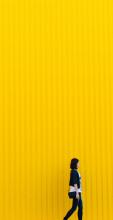 Side of a girl walking away against a yellow background