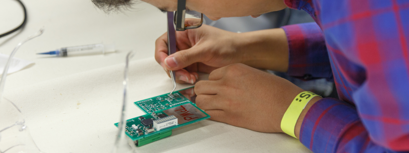 A student solders an electronic circuit