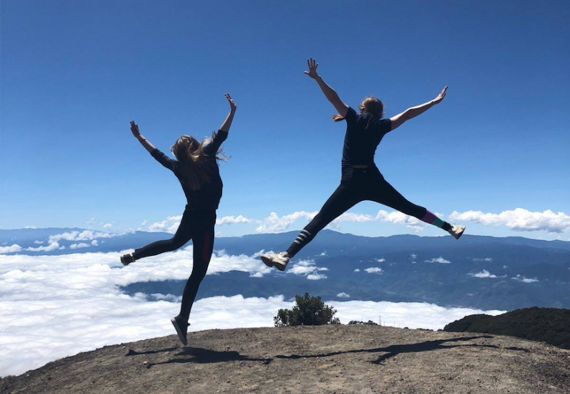 Photo of two girls jumping on top of a mountain