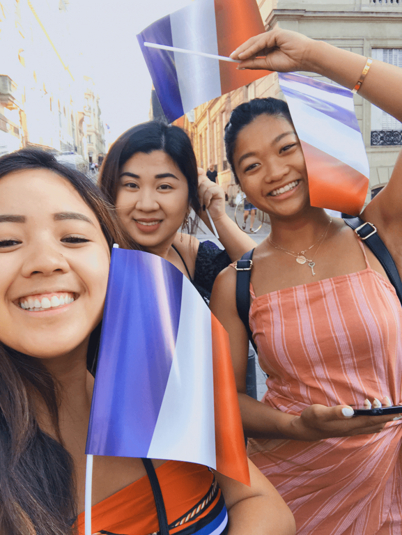 FASS France ICS study tour three girls holding French flags at a festival