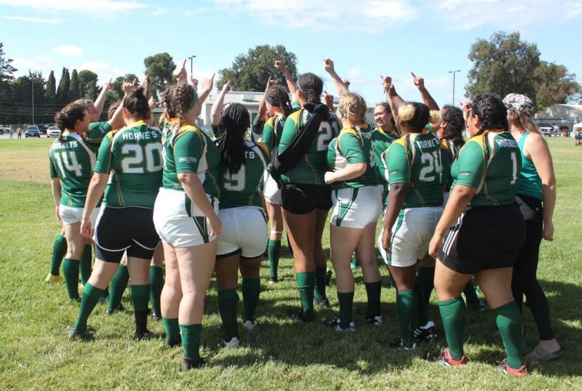 FASS ICS Latino USA study tour A female sports team wearing green jerseys high fives on the grass oval