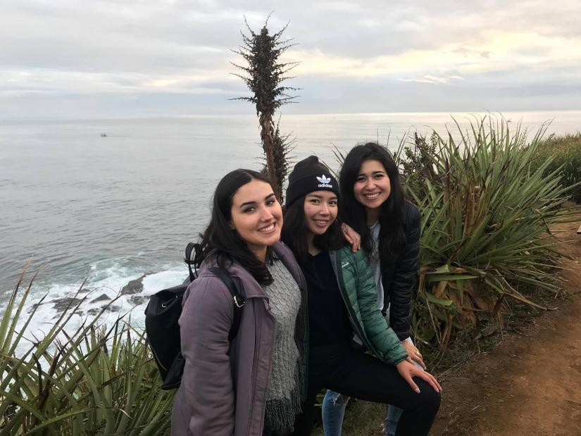 Rochelle with two female friends standing and smiling on the coastline