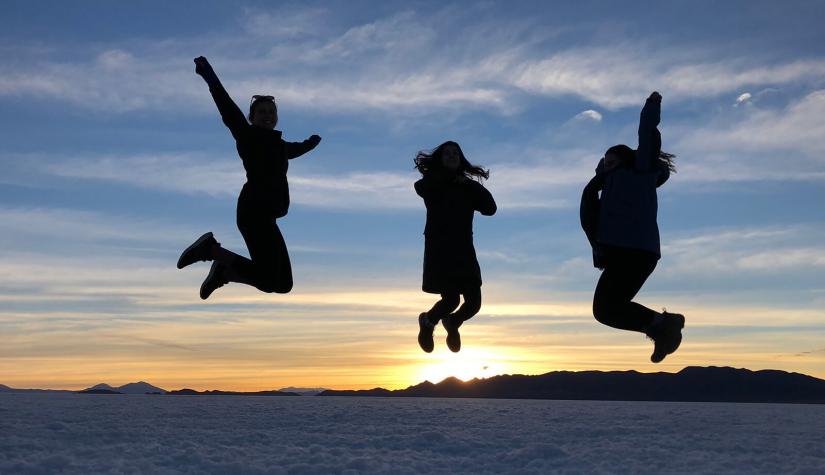 Three jumping figures silhouetted against the sunset