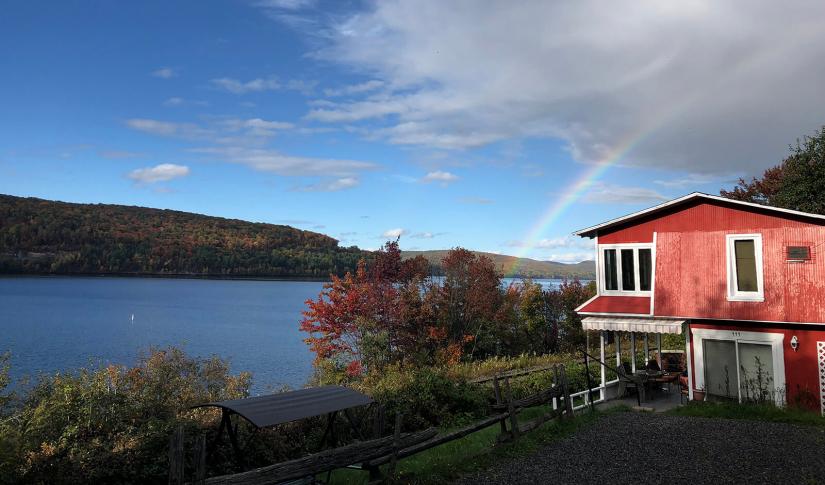 A red cabin next to a large lake with a rainbow in Ottawa