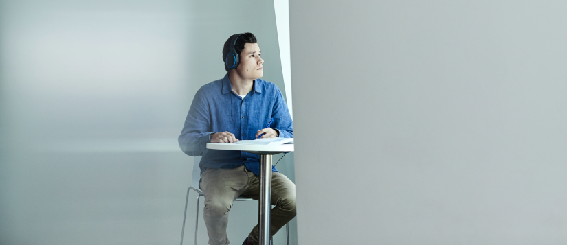 A male student sitting at a desk with headphones on
