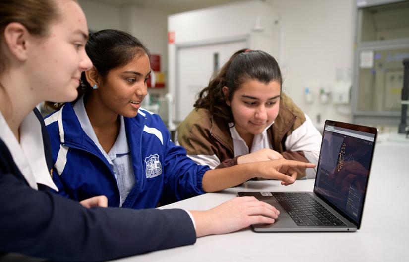 Three school girls looking at a laptop