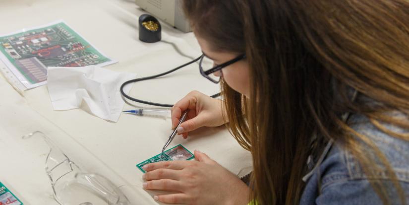 A female high school student soldering a circuit board