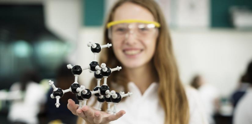 A teenage girl holding a science atom structure model