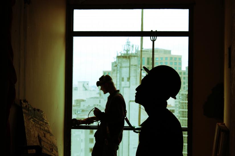 Silhouette of two construction workers inside a building