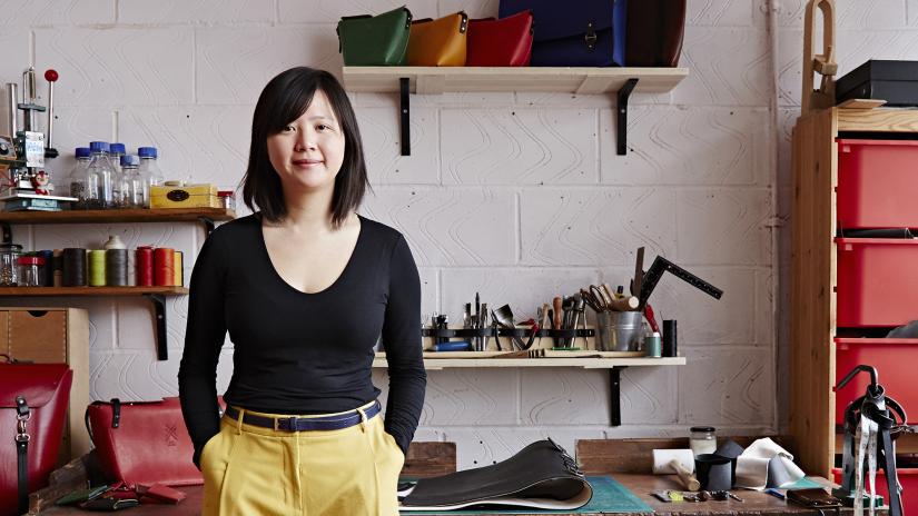 Candice Lau in her workshop surrounded by tools and finished bags.