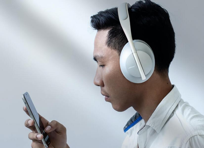 Man making selections on his phone and listening with white headphones