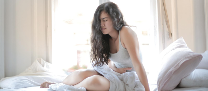 A woman holds her stomach in pain