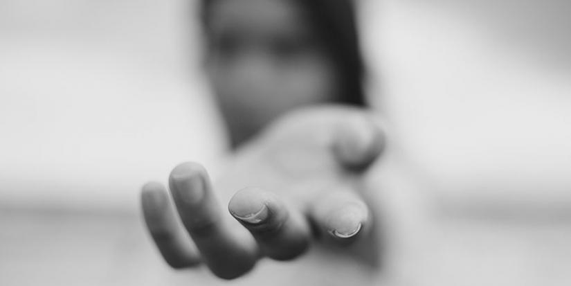Black and white blurred image of a woman with her hand stretched out.