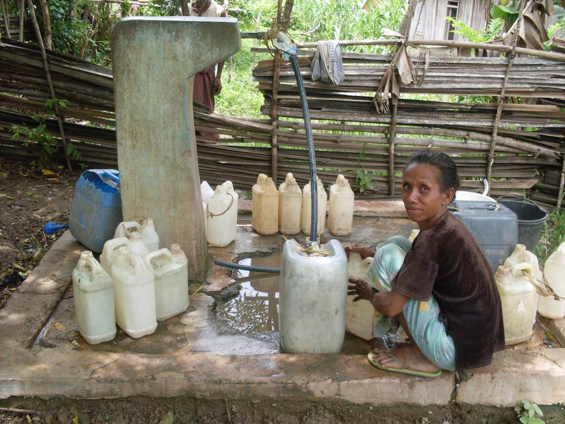 woman filling water containers at an outdoor pump