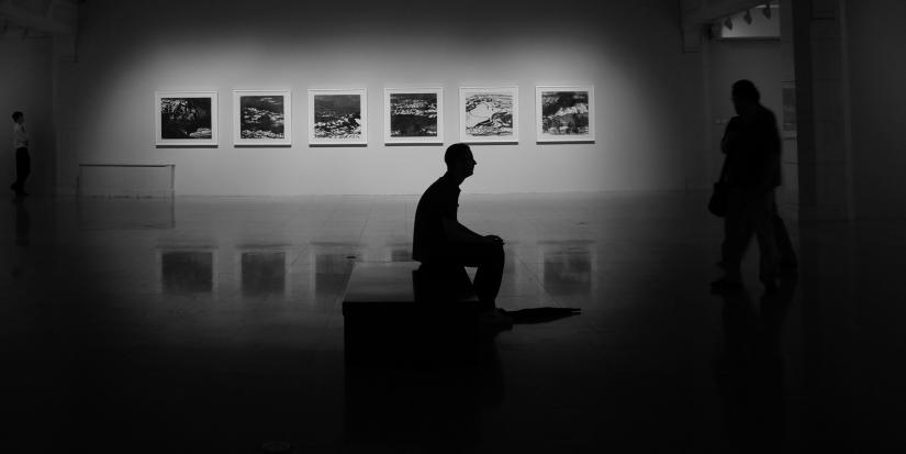 Man sitting on a couch in an art gallery.
