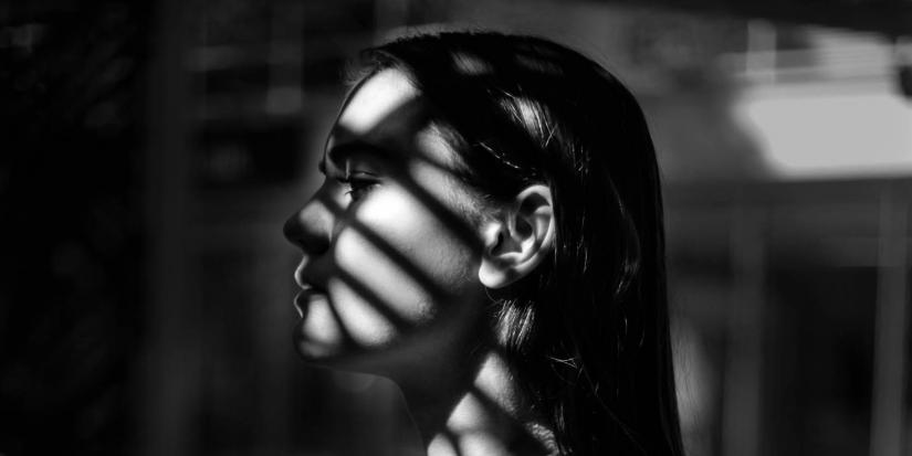 Black and white image of a woman with a shadow across her face.