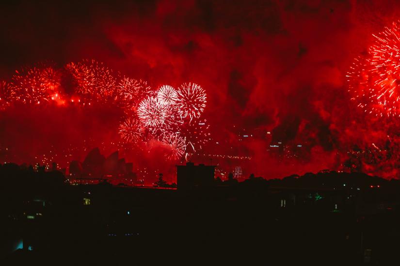 Red fireworks over Sydney Harbour with silhouette of Opera House