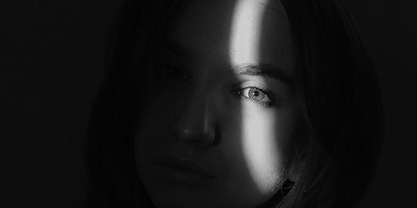 Black and white image of a women with a shadow across her face.
