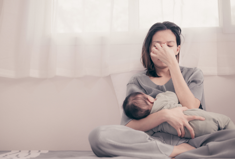 Tired and overwhelmed mum breastfeeding