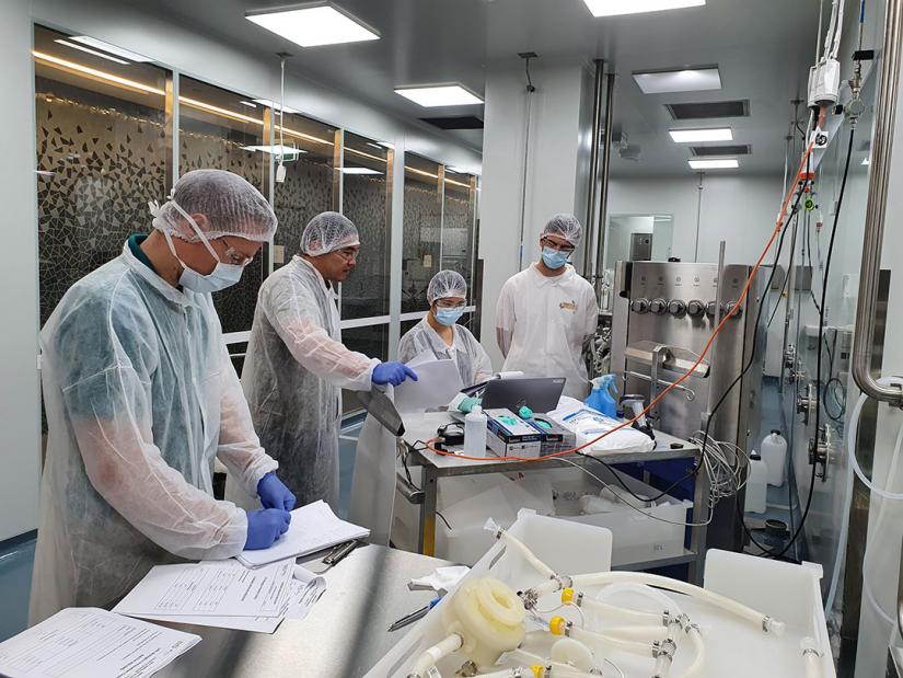 Four people in personal protective gear in lab