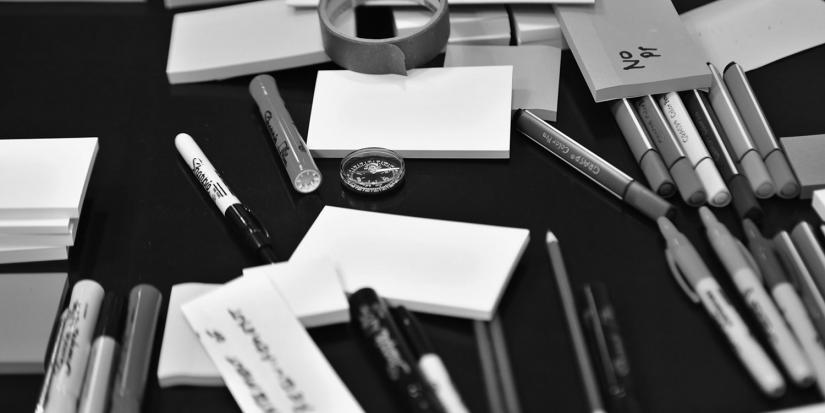 Black and white image of pens and sticky notes