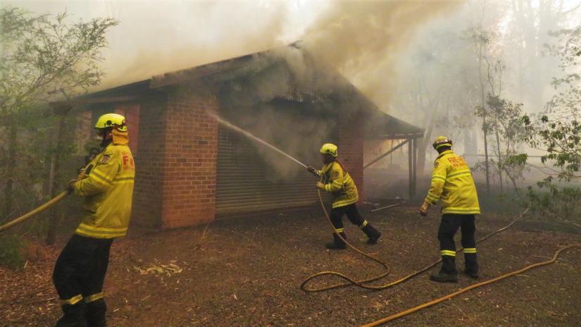 Fire and Rescue NSW firefighters work to save a burning house
