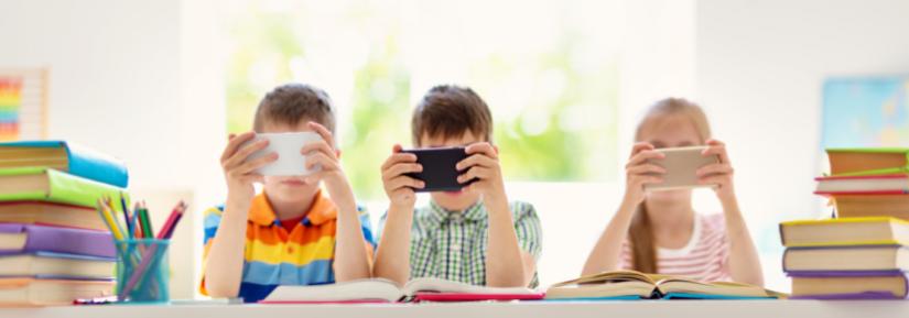 Three children with mobile phones in the classroom