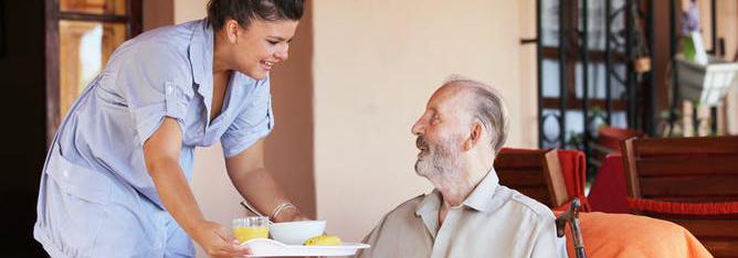 Aged care staff member serves meal to resident