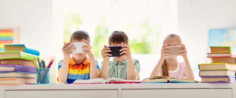 Three children with mobile phones in the classroom