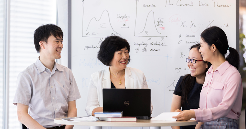 Distinguished Professor Jie Lu (second from left) is sitting with a laptop in front of her, together with three other early career researchers from AAII discussing research and smiling at each other.