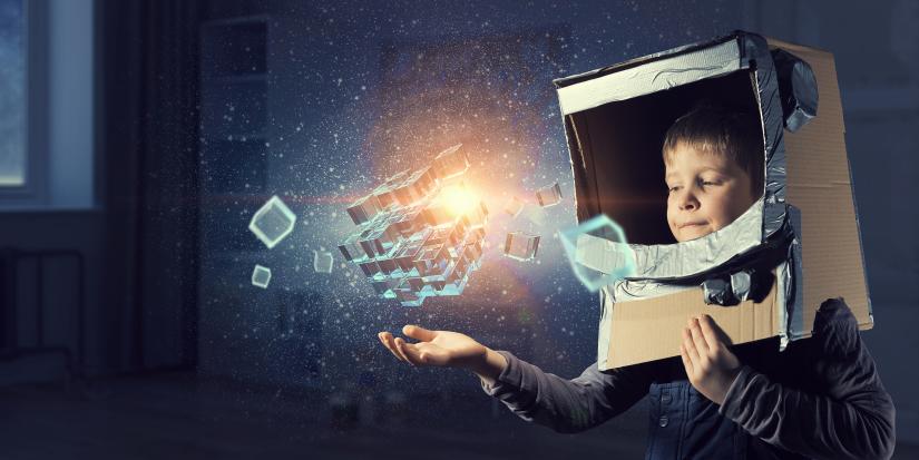 Image of boy in cardboard helmet interacting with light-filled boxes
