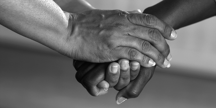 Black and white image of two people holding hands.