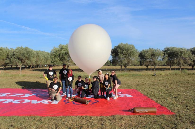 PAAS students pose underneath a large white balloon