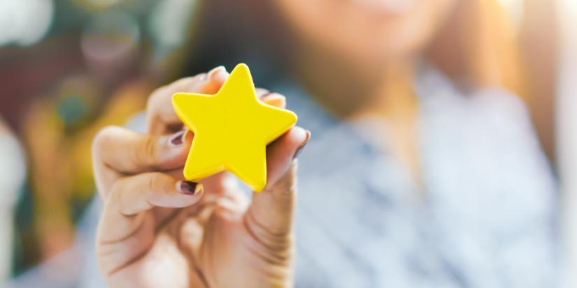 Close up image of a hand holding a 3D yellow star