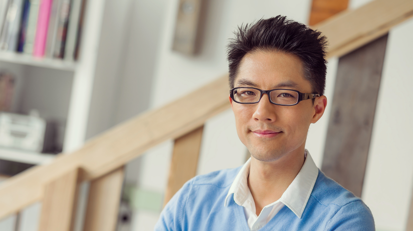 Young Asian man in glasses, white collared shirt and blue jumper